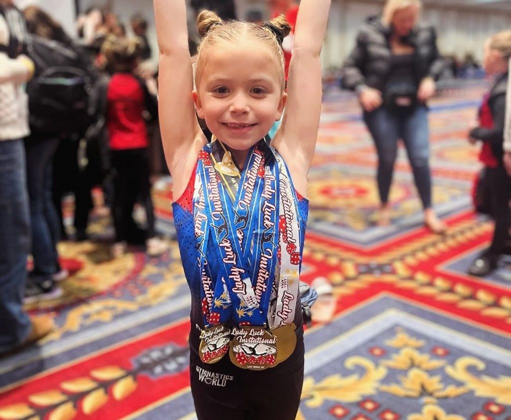 Girl gymnast with medals smiling and saluting