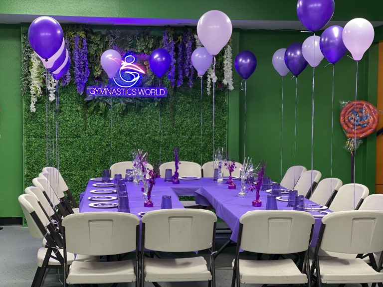 Birthday Party room with green background and purple table decorations and setup. Purple balloons.