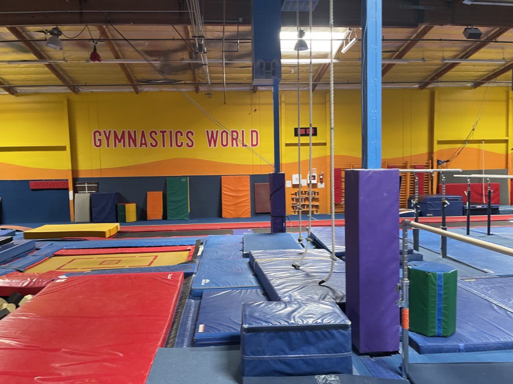 Gymnastics Facility with gymnastics equipment Colorful Mats - In Ground Yellow Trampoline and rope hanging from ceiling.