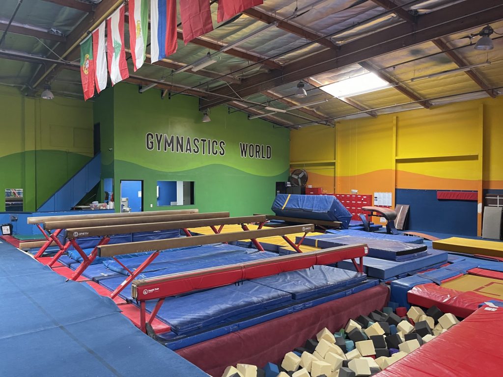 Gymnastics Facility with gymnastics equipment Colorful Mats - Balance Beam Area over Blue Mats