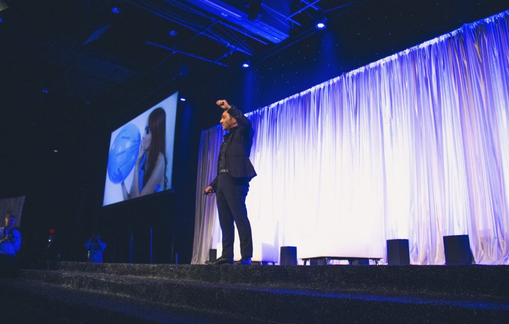 Freddy Behin - Speaking On Stage wearing a black suit